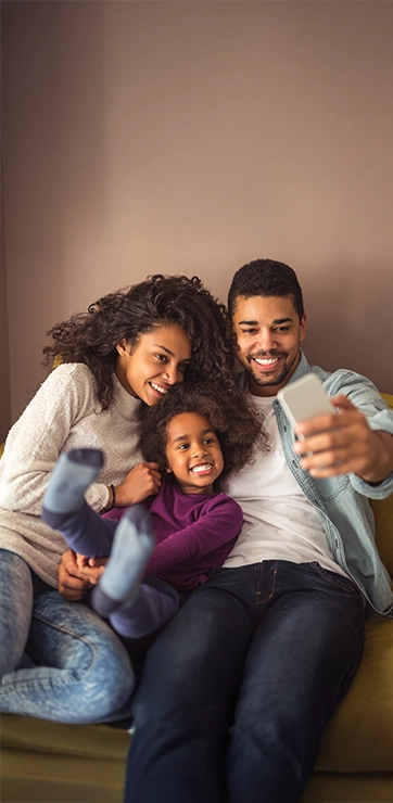 Happy Family Smiling On Couch Taking A Selfie