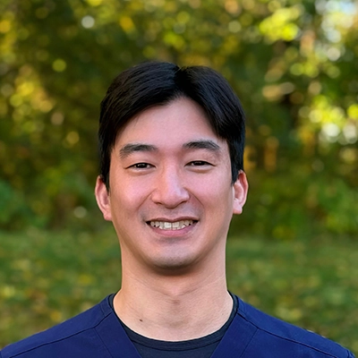 Dentist Joey Oh Smiling Outdoors In Scrubs